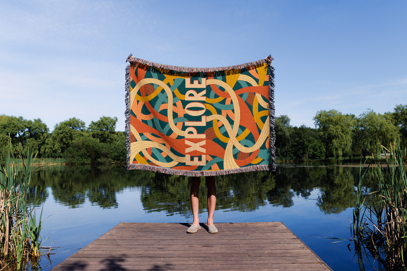 Maquette produit d'une couverture tissée avec une illustration positive dessus. Le mot Explore est mis en valeur. Mockup of an uplifting illustration on a woven blanket. The word Explore is the main subject. Illustration @AliceLambertDesign